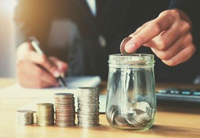 putting coins in a jar representing college and university fees