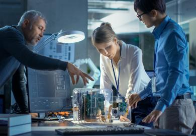 Scientists and business people discuss a computer component