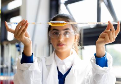 An Asian student holds a pipette level, symbolising equlaity in international collaboration