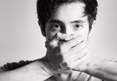 A man with his hands over his mouth, symbolising self-censorship