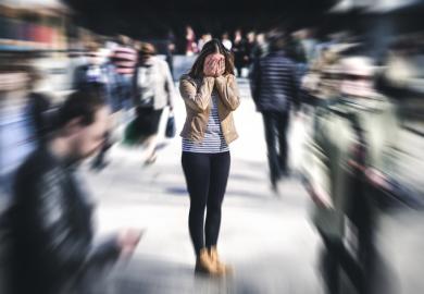 A woman in a crowd covers her face in shame