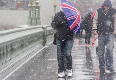 Man crosses bridge with Union Jack umbrella as snow falls