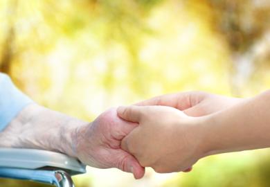 Old woman olding carer's hand