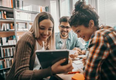 A group of students look at a tablet
