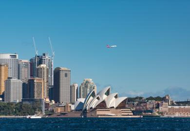 A plane flies over Sydney Opera House