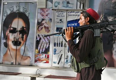 A Taliban fighter walks past a beauty salon with images of women defaced using spray paint in Shar-e-Naw in Kabul, Afghanistan on 18 August 2021.