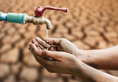 A hand under a tap dripping water, symbolising cuts to the UK’s ODA spending