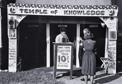 Historical photo of a fortune teller's booth, the Temple of Knowledge, showing advertising posters, admission taker, and two women customers waiting their turns. To illustrate that admissions on predicted A-level grades look foolish in AI era.