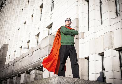 Caped geek superhero standing on pedestal