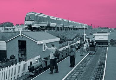 Miniature railway next to real train