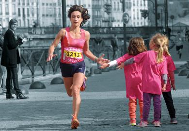 A female runner giving children a high five as she runs past.