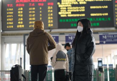 A traveller in a face mask at a railway station in Suzhou, China, illustrating the downturn in Chinese international students post-Covid