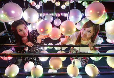 Two women look at pollen robots in Japan