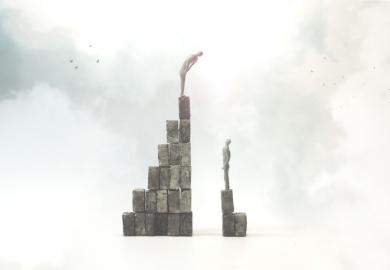 A man on a tall pile of bricks looks down on one on a smaller pile