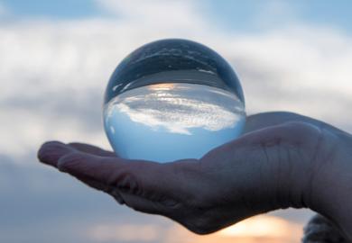 Hand holding a glass globe with a reflection of a sunset