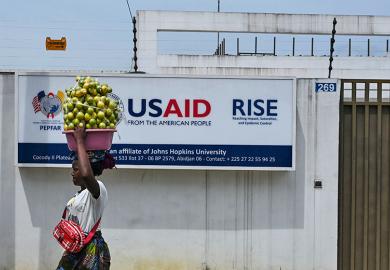 A street vendor walks past the USAID office in Abidjan, Ivory Coast