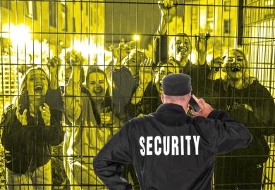 Security guard in front of fence with crowd smiling people behind