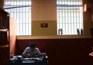 prisoner at desk with book