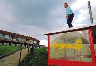 Boys playing on bus shelter on run down council estate; Bradford UK to illustrate social mobility