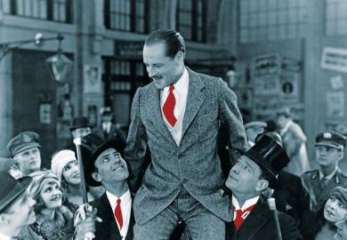 Man carried on shoulders above crowd to illustrate Who’s a jolly good fellow?