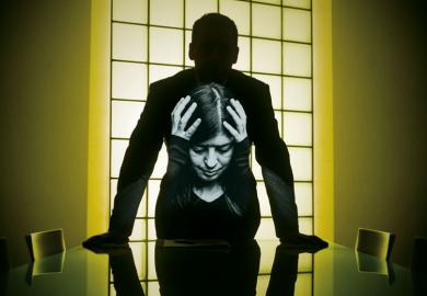 Shadow person standing at desk with image of lady holding her head  within the shadow body shape