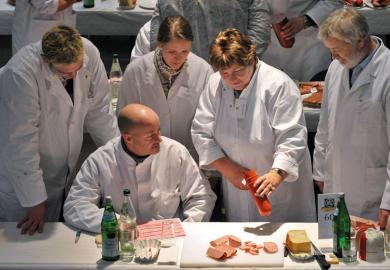 Food testers evaluate products during a quality check for ham and sausage as a metaphor for quality and control