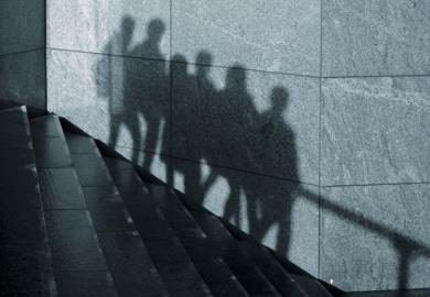 The shadows of anonymous people walking in one direction down stairs are seen on a wall in London as a metaphor for some students abusing privacy allowances