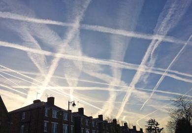 A pattern of condensation trails produced by aircraft engine exhausts, criss-cross the sky to illustrate Fragility in the system