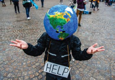 A man with an earth ball on his head and help sign makes hand gesture
