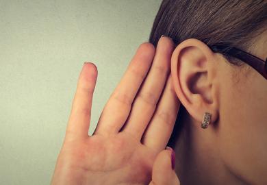 Woman cupping hand to ear to listen