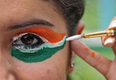 Woman painting eyes in colours of flag of India