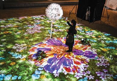 A woman uses her smartphone in an interactive multimedia installation that connects Singapore and Japan in a time of separation, in Tokyo on November 13, 2020