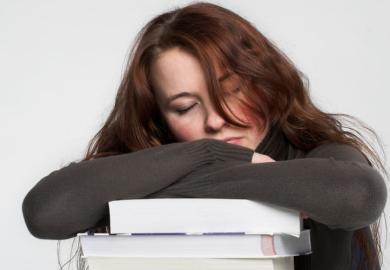 Young woman asleep on pile of books