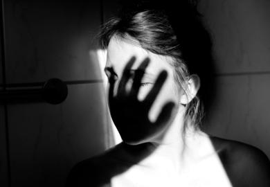 Young woman with shadow of hand over face