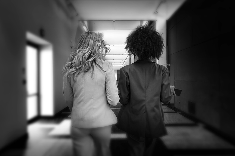 Two women walking down a corridor. To illustrate Agnieszka Piotrowska leaving a meeting when the only Black person present was asked to leave.