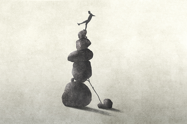 Illustration of person teetering on top of an unstable tower made of stones. To illustrate the precarity of institutions most exposed to the current funding crisis – those without research depth, commercial pipelines or endowment income. Illustration of person teetering on top of an unstable tower made of stones. To illustrate the precarity of institutions most exposed to the current funding crisis – those without research depth, commercial pipelines or endowment income.