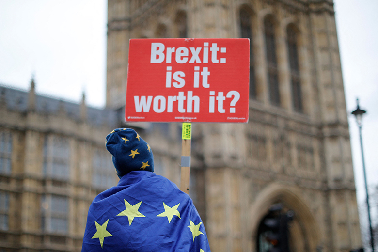 Anti-Brexit supporters hold placards and flags as they demonstrate outside the Houses of Parliament on 14 January, 2019. A placard reads 'Brexit: is it worth it?'.