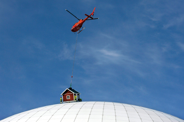 Helicopter lowers cottage onto Ericsson Globe Arena, Stockholm, Sweden