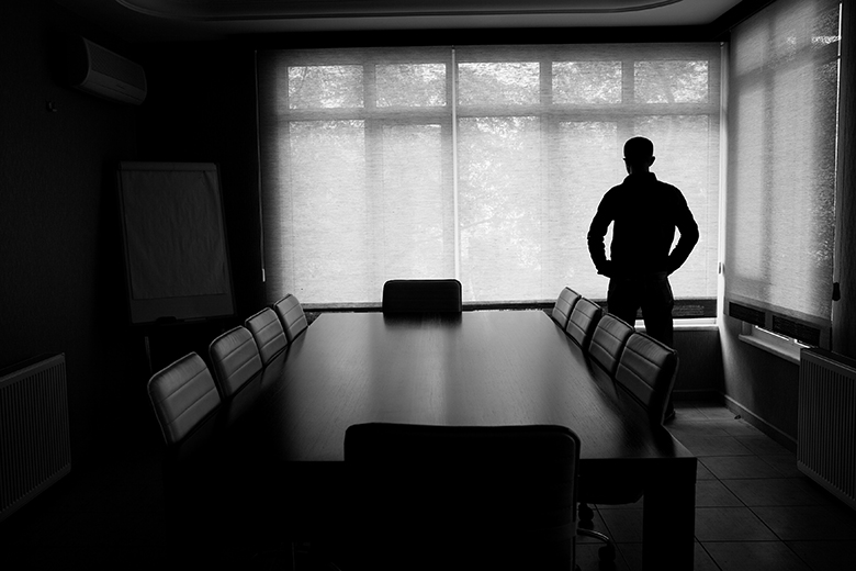 A man standing alone in a room, to illustrate a lack of adequate supervision for doctoral students.