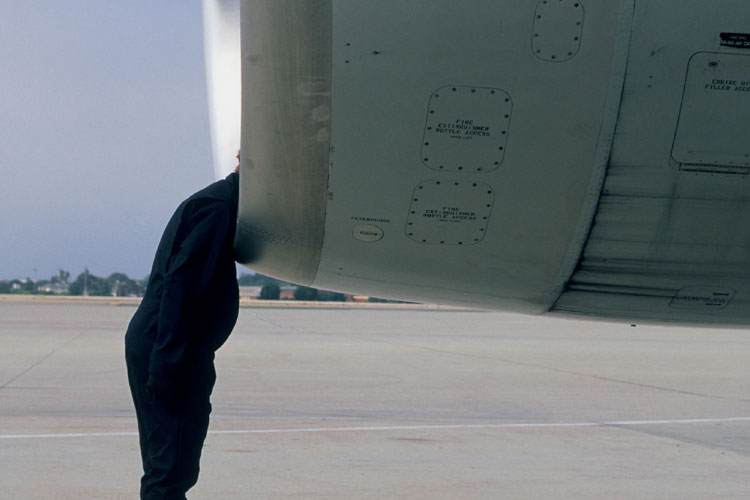 Man leaning head into jet engine