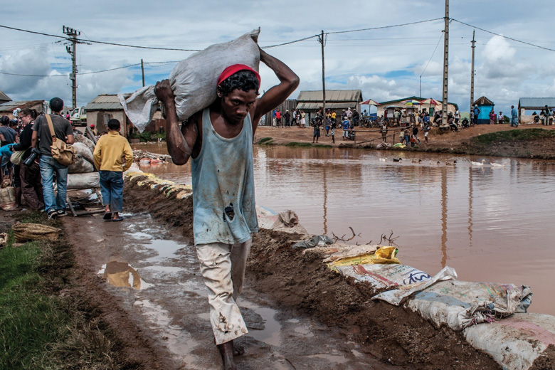 Man using sandbag to reduce flood damage, Madagascar