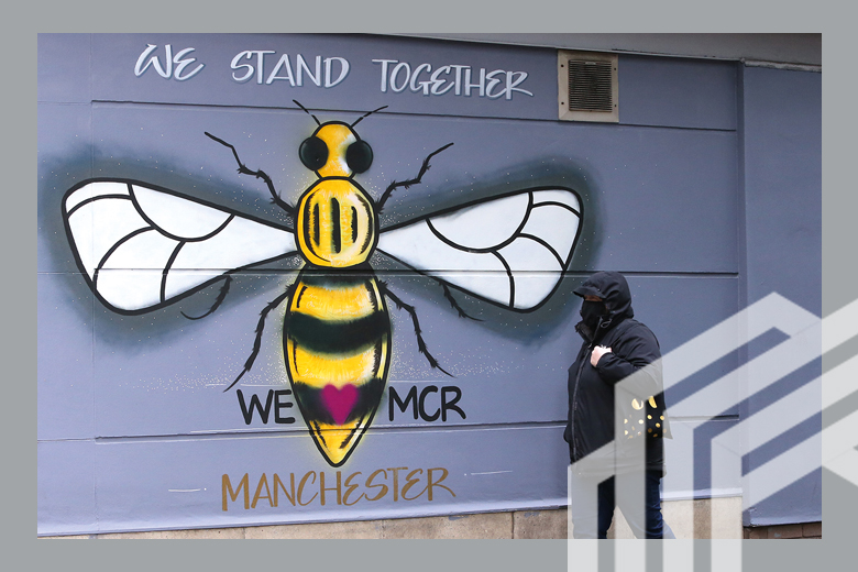 A woman wearing a face mask is seen walking past street art depicting the Manchester bee on 17 February, 2021 in Manchester, England. A woman wearing a face mask is seen walking past street art depicting the Manchester bee on 17 February, 2021 in Manchester, England.