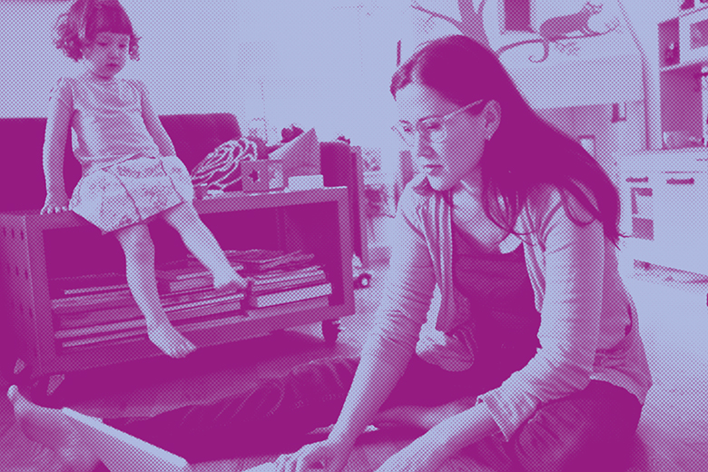 Mother working on laptop while looking after daughter