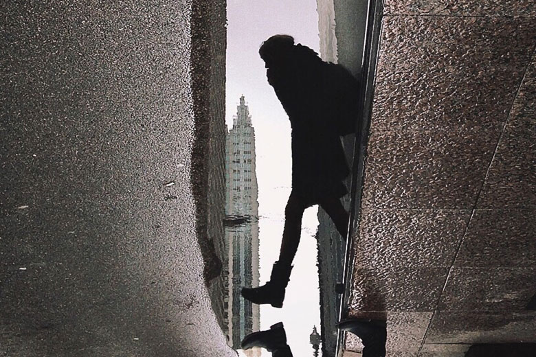 Reflection in puddle of person stepping into street