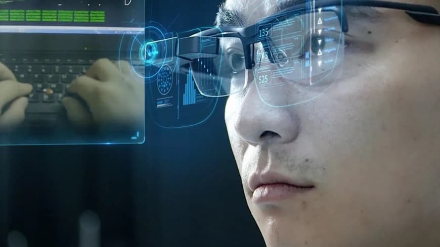 A man wearing computer generated glasses looking into computer screen