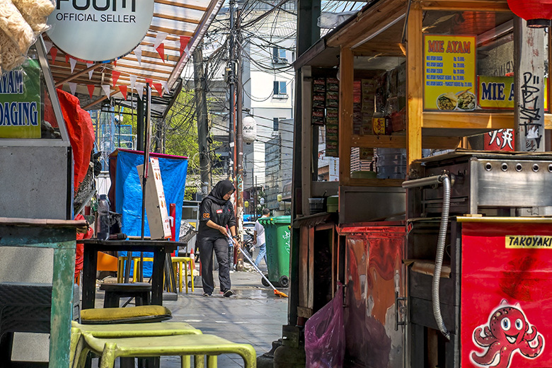 A restaurant employee mops the floor while opening for business in Jakarta on 7 August 2026. To illustrate graduates working in jobs that do not require the qualifications they spent years acquiring.