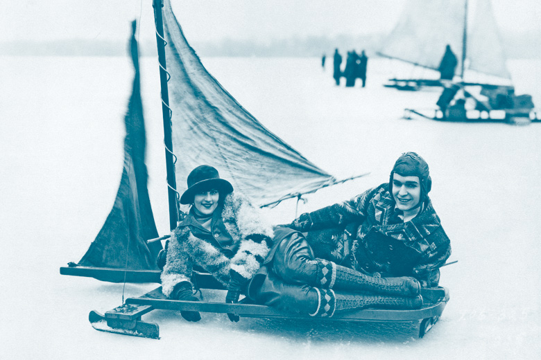Smiling couple lying on ice windsurfing board