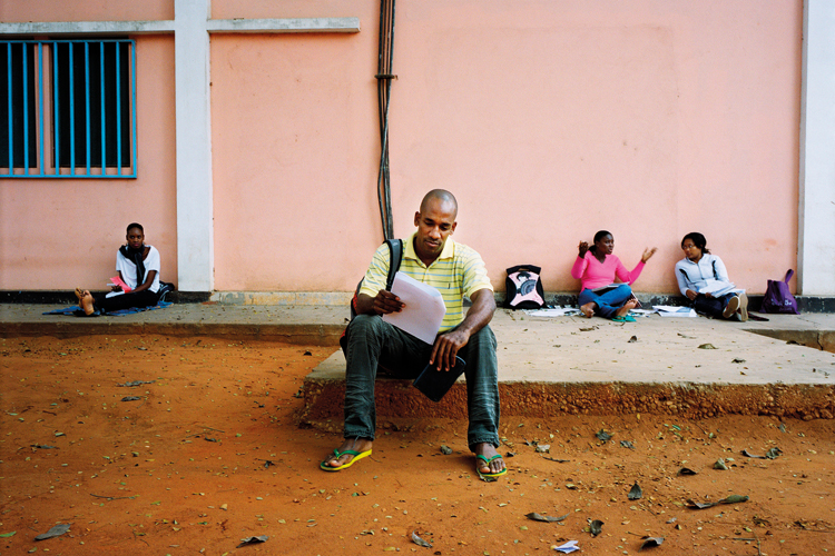 Student reading outside Agostinho Neto University