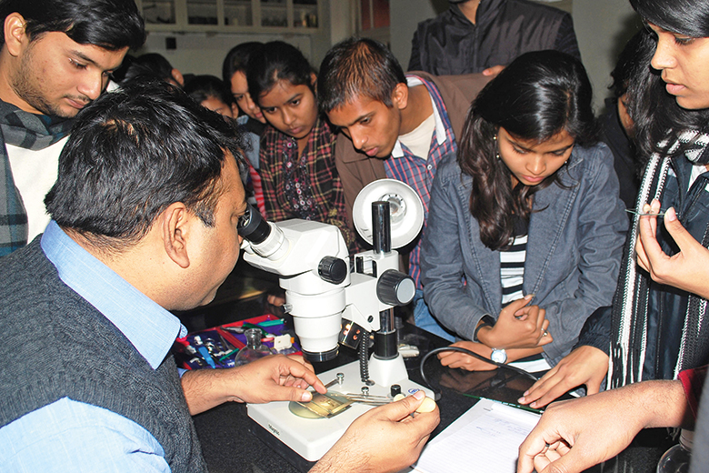 Students gather around a microscope