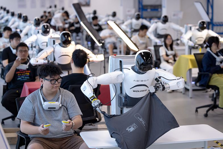 Humanoid robots follow technicians to learn job skills at the data collection area of an embodied AI robot innovation centre on 14 September 2025 in Shaoxing, Zhejiang Province of China. Staff members use controllers to “guide” the humanoid robots.